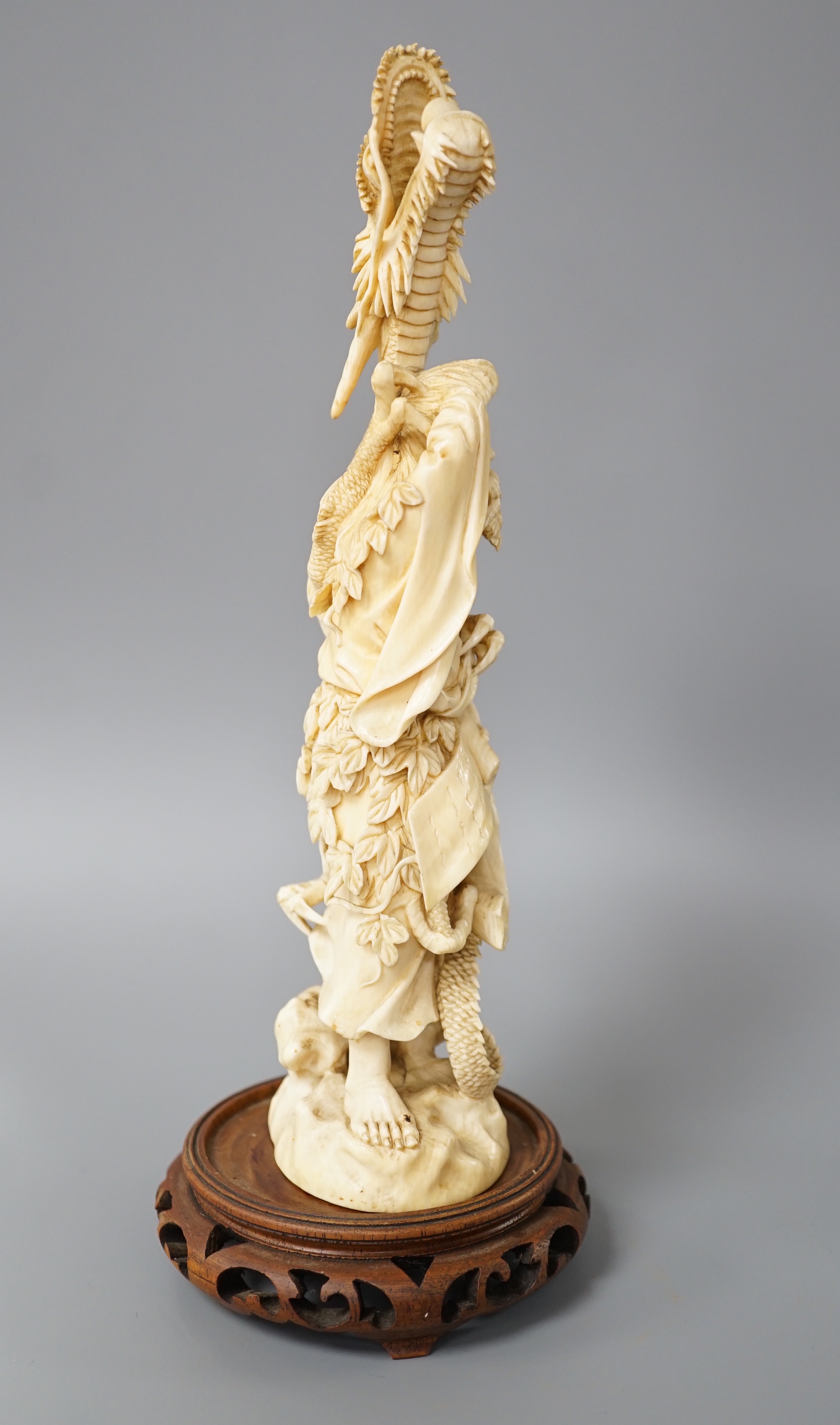 A Japanese ivory okimono of Shoshi Sennin and a dragon, early 20th century, signed, associated wood stand, 24cm excl stand